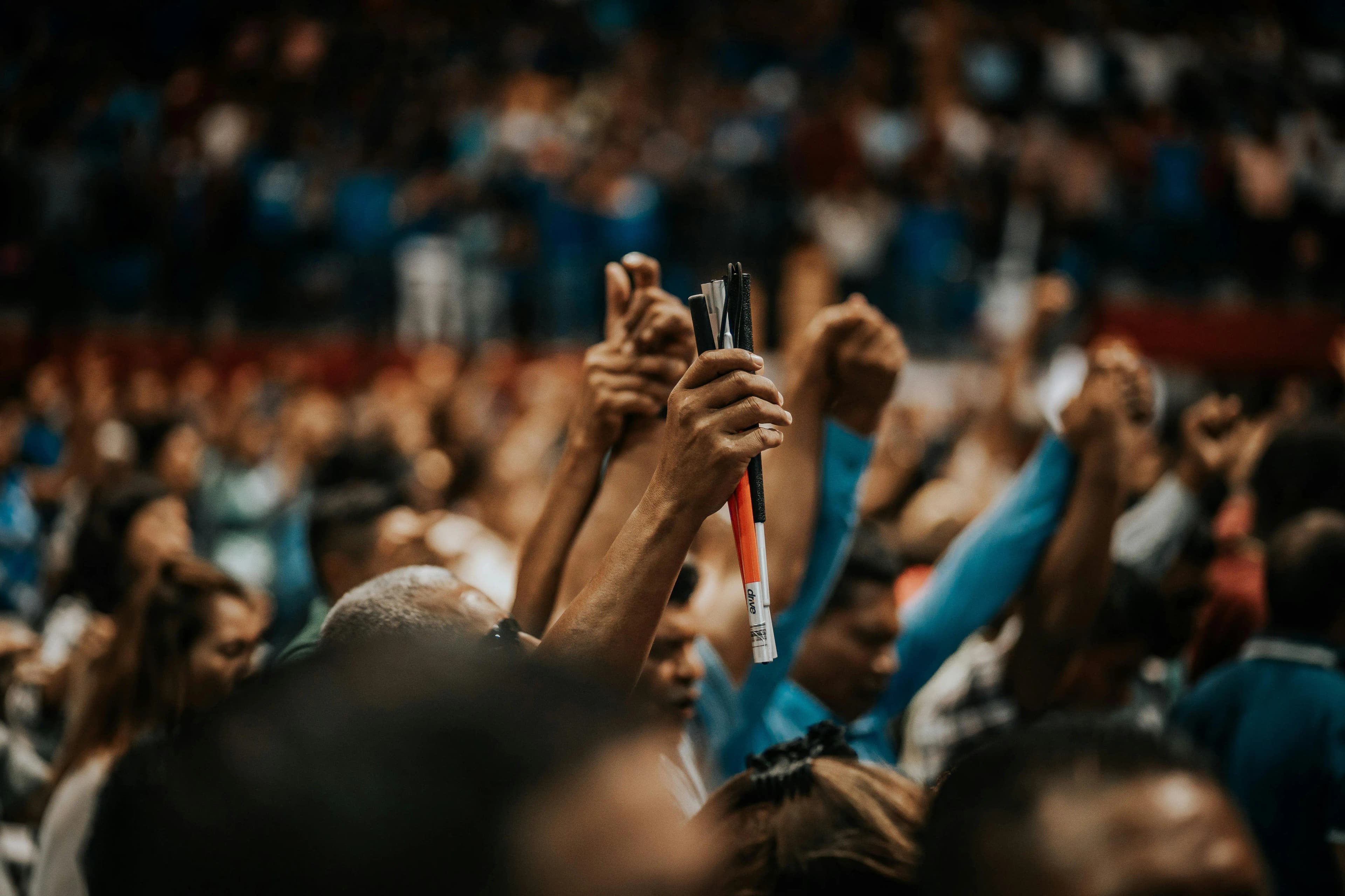 A mass of people point hands to the sky